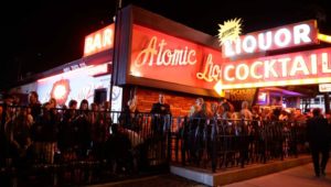 Outside of Atomic Liquors, neon signs saying “Liquor and Cocktails,” people lined up outside the bar